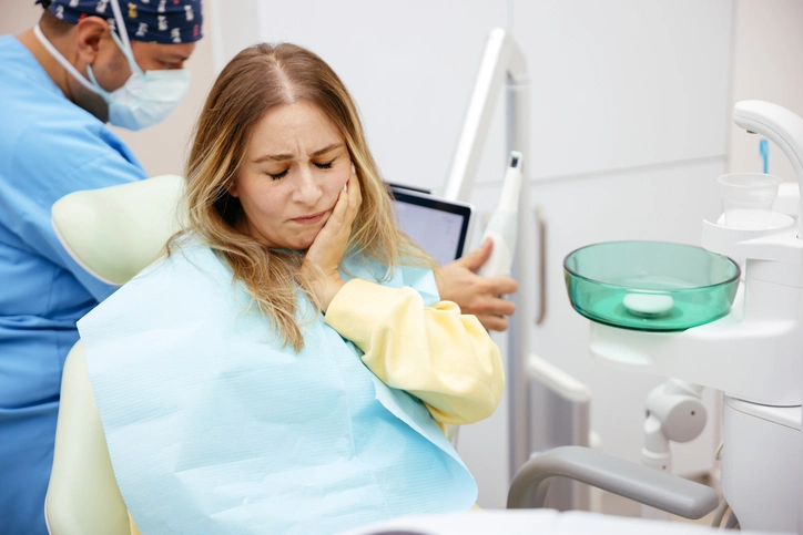 Patient holding face in discomfort during emergency dental visit in Arlington Heights, IL