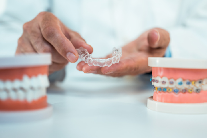 Dentist explaining Invisalign treatment using a clear aligner model in Arlington Heights, IL