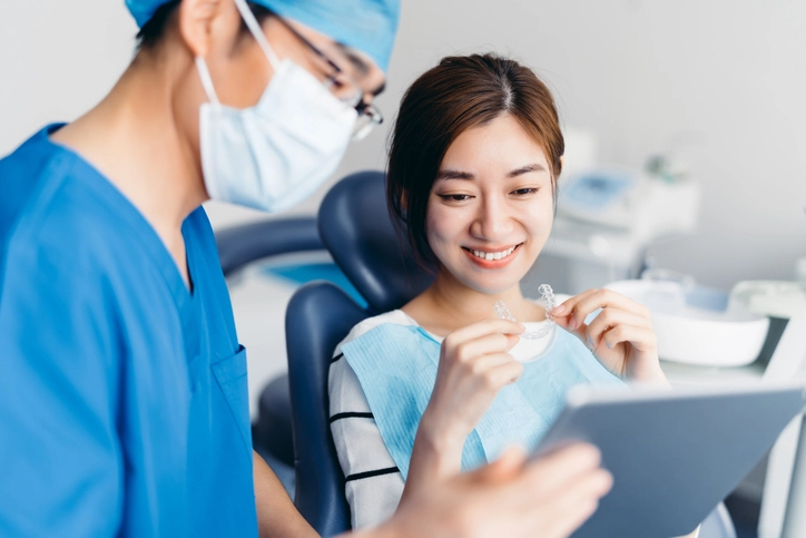Dentist shows Invisalign on tablet to patient holding aligners in Arlington Heights, IL