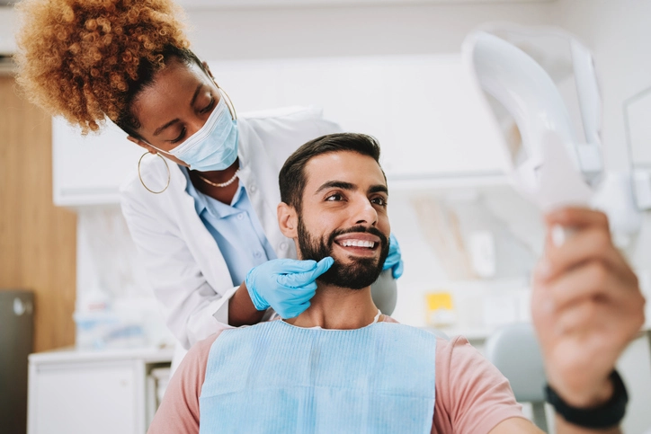 Patient in dental chair smiling into the mirror as the dentist examines teeth in Arlington Heights