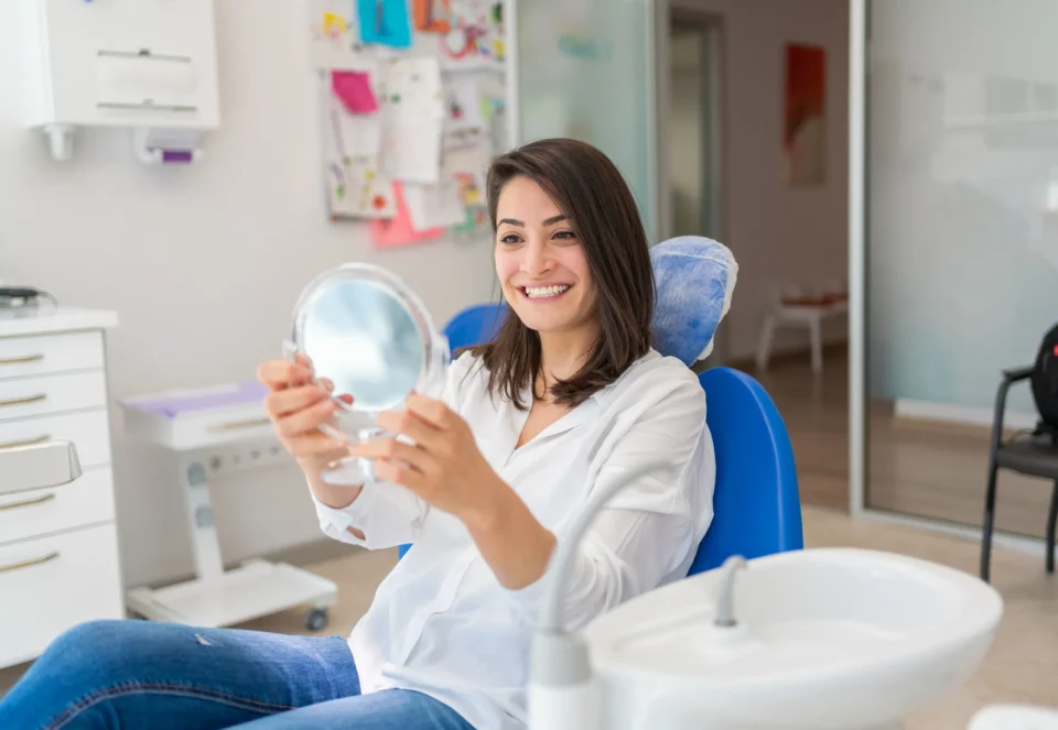 Young lady in dental chair holding a mirror after teeth whitening in Arlington Heights, IL